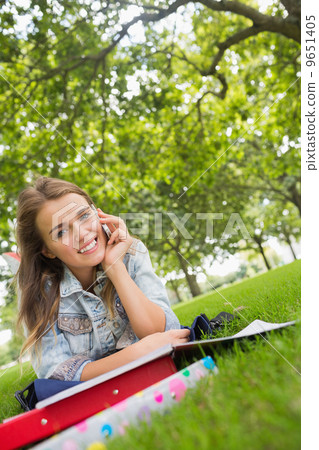 Young smiling student lying on the grass on the phone 9651405