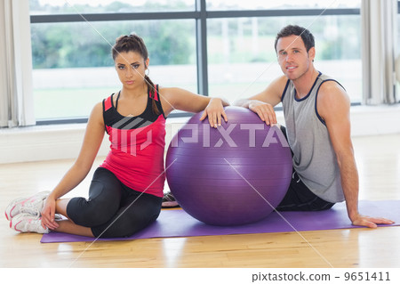 Young woman and man with fitness ball sitting at gym Young woman and man with fitness ball sitting at gym 9651411