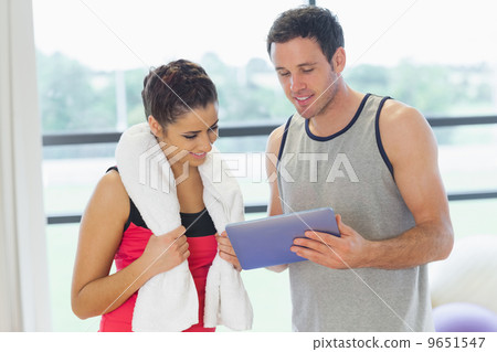 Fit couple looking at digital table in exercise room 9651547