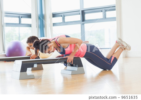 Two women performing step aerobics exercise in gym Two women performing step aerobics exercise in gym 9651635
