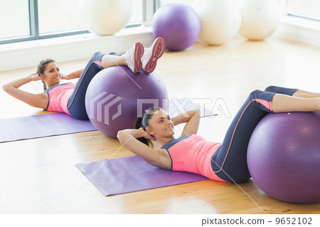 Two young women exercising with fitness balls at gym 9652102