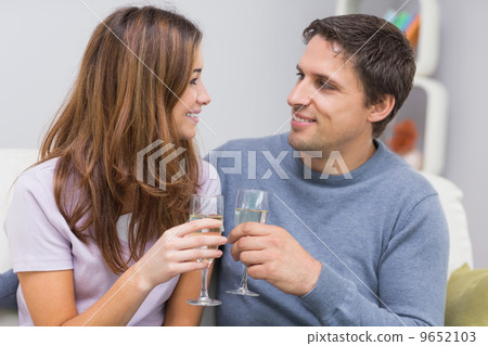 Romantic smiling young couple toasting flutes at home Romantic smiling young couple toasting flutes at home 9652103