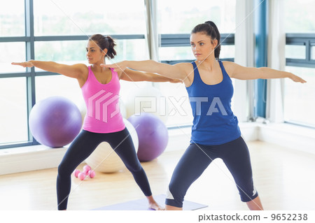 Two sporty women stretching hands at yoga class 9652238