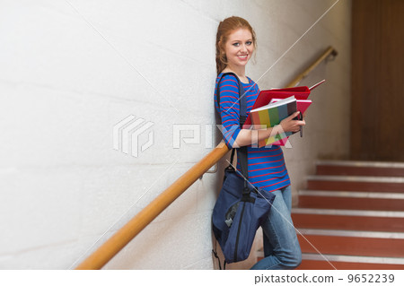Smiling young student holding her notes on the stairs 9652239