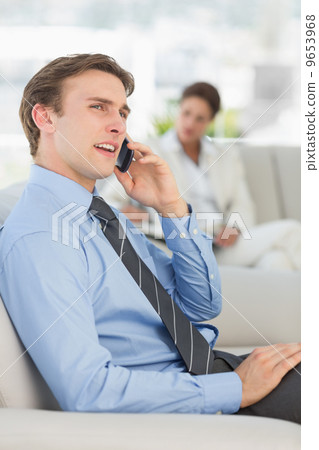 Cheerful businessman on the phone sitting on sofa Cheerful businessman on the phone sitting on sofa 9653968