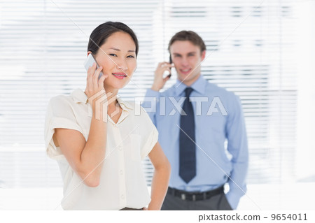 Businesswoman and man using cellphones in office 9654011