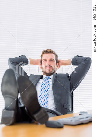 Relaxed businessman sitting with legs on desk 9654012