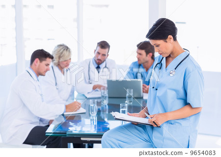 Female surgeon looking at reports with colleagues in meeting 9654083