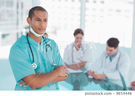 Surgeon standing with group around table in hospital 9654446
