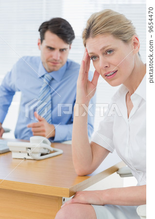 Upset businesswoman with man working on laptop 9654470