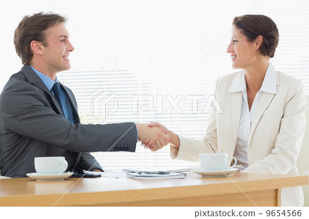 Smartly dressed couple shaking hands in business meeting Smartly dressed couple shaking hands in business meeting 9654566