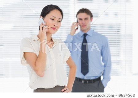 Businesswoman and man using cellphones in office 9654568