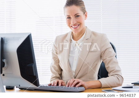 Businesswoman using computer at office desk 9654837
