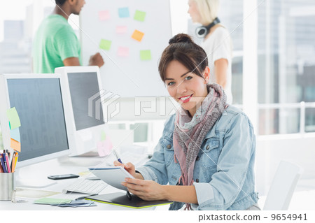 Artist drawing something on graphic tablet with colleagues behin Artist drawing something on graphic tablet with colleagues behin 9654941