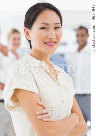 Pretty asian businesswoman standing with team behind her Pretty asian businesswoman standing with team behind her 9654942