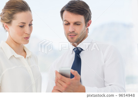 Smartly dressed colleagues looking at mobile phone Smartly dressed colleagues looking at mobile phone 9654948
