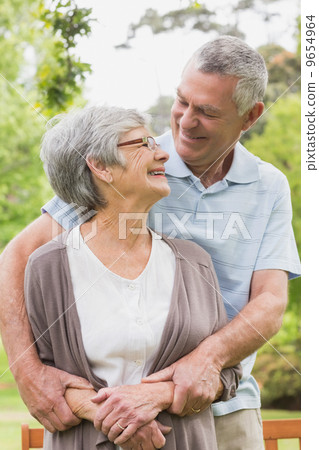Senior man embracing woman from behind at park Senior man embracing woman from behind at park 9654964
