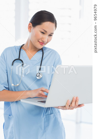Concentrated female surgeon using a laptop Concentrated female surgeon using a laptop 9654979