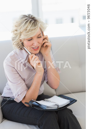 Female secretary with diary while using mobile phone Female secretary with diary while using mobile phone 9655046