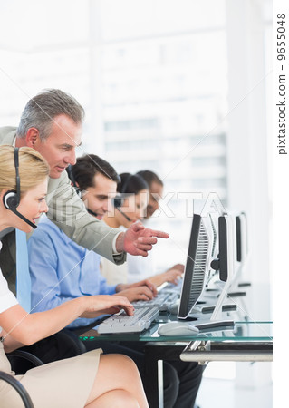Manager and executives with headsets using computers 9655048
