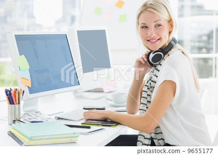 Casual woman with headset at computer desk in office Casual woman with headset at computer desk in office 9655177