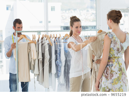 Seller helping shopper choose clothes in store 9655219