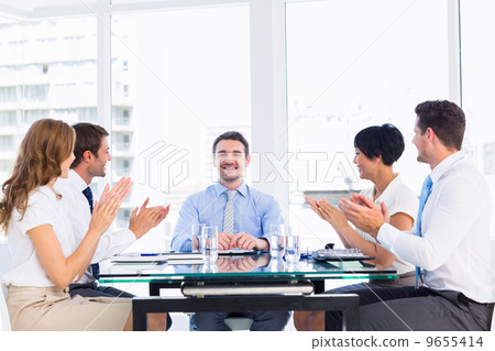 Executives clapping around conference table Executives clapping around conference table 9655414