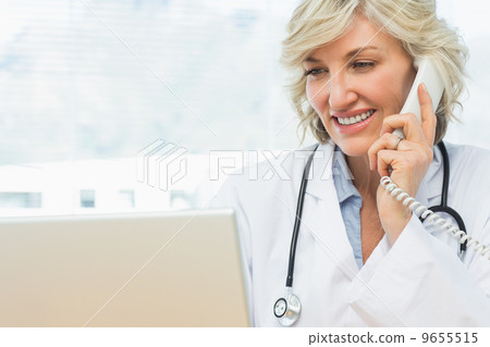 Female doctor using laptop and phone in medical office Female doctor using laptop and phone in medical office 9655515