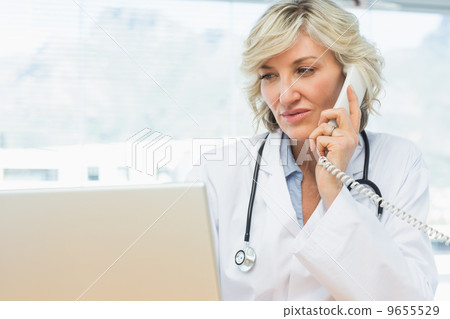 Doctor using laptop and phone in medical office Doctor using laptop and phone in medical office 9655529