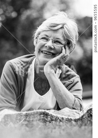 Smiling senior woman lying at park Smiling senior woman lying at park 9655595