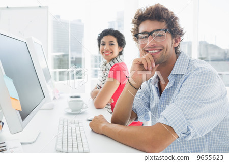 Smiling casual couple at desk in office 9655623