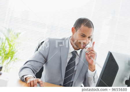 Businessman using computer and phone at office Businessman using computer and phone at office 9655680