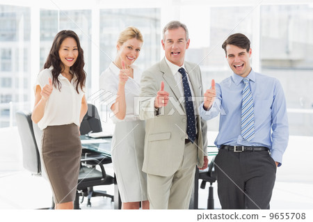 Business team giving thumbs up to the camera 9655708
