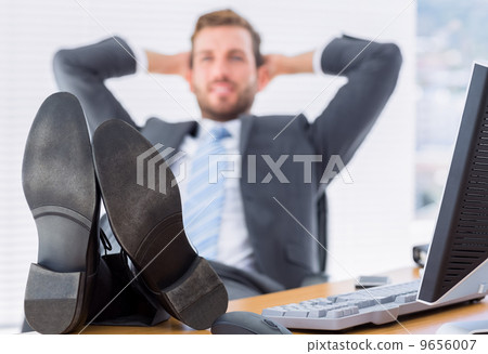 Relaxed businessman sitting with legs on desk 9656007