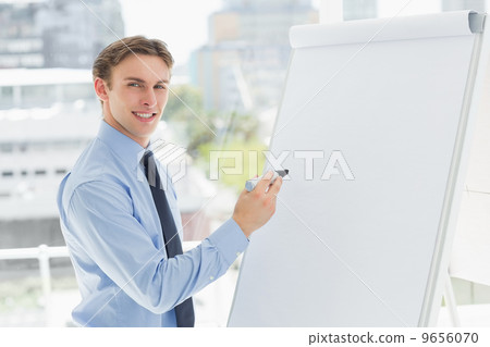 Young smiling businessman writing on whiteboard with marker Young smiling businessman writing on whiteboard with marker 9656070