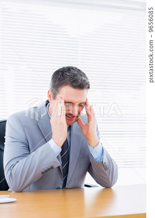 Businessman with severe headache at office desk 9656085
