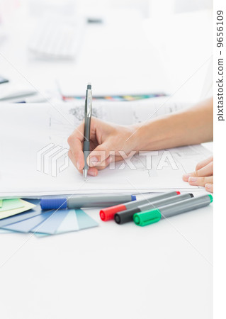 Artist drawing something on paper with pen at office Artist drawing something on paper with pen at office 9656109