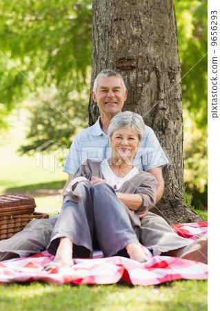 Senior man embracing woman from behind at park 9656293