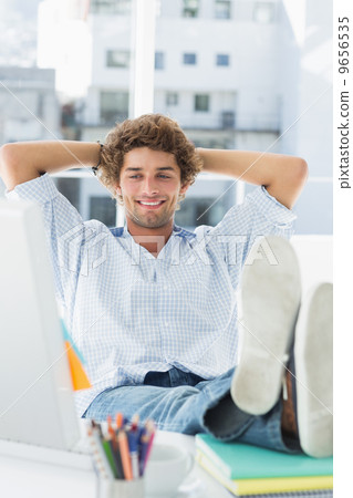 Casual young man with legs on desk in office Casual young man with legs on desk in office 9656535