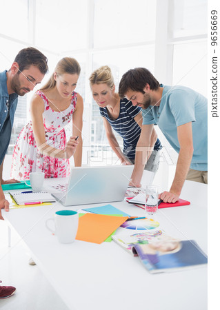 Casual business people using laptop together Casual business people using laptop together 9656669
