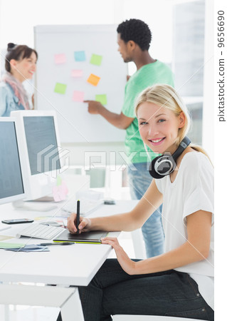 Artist drawing something on graphic tablet with colleagues behin Artist drawing something on graphic tablet with colleagues behin 9656690