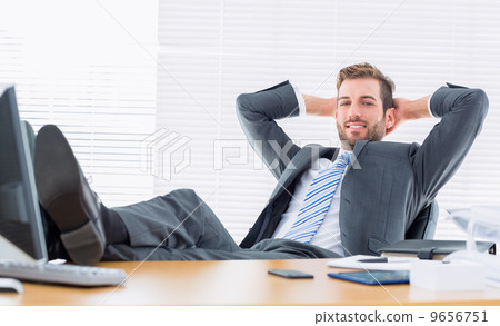 Relaxed confident businessman sitting with legs on desk 9656751