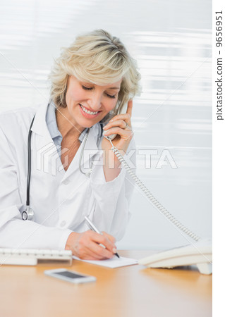 Doctor using phone while writing notes at medical office 9656951