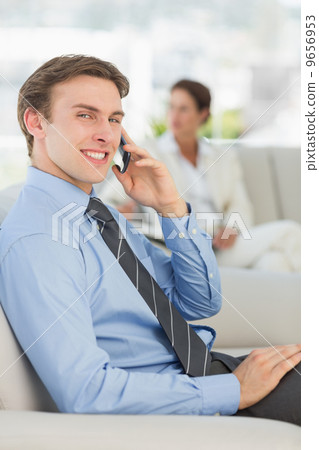 Smiling businessman on the phone sitting on sofa 9656953