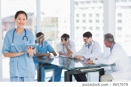 Surgeon using digital tablet with group around table in hospital Surgeon using digital tablet with group around table in hospital 9657079