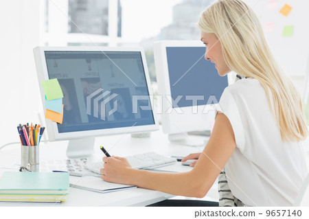Casual young woman using computer in office Casual young woman using computer in office 9657140