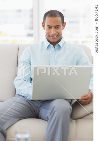 Happy businessman working on laptop on the couch 9657143