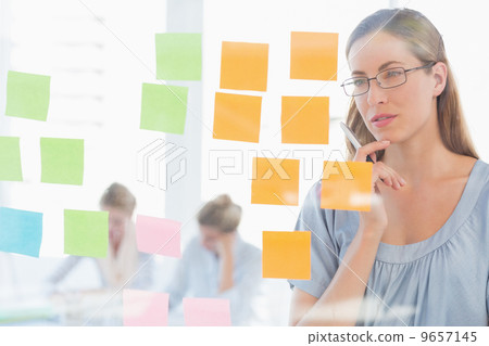Concentrated artist looking at colorful sticky notes Concentrated artist looking at colorful sticky notes 9657145