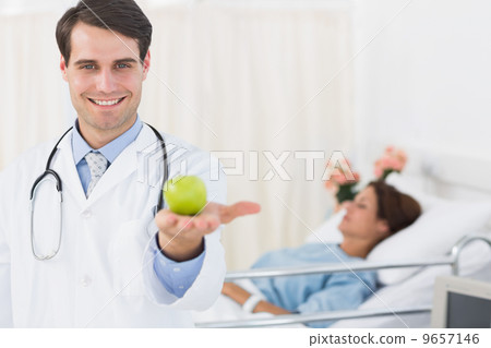 Smiling doctor holding apple with patient in hospital Smiling doctor holding apple with patient in hospital 9657146
