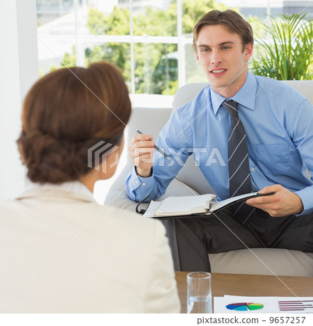 Young businessman scheduling with colleague sitting on couch 9657257